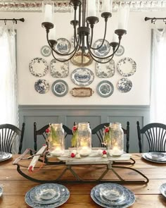 a dining room table with plates on it and candles in mason jars at the center