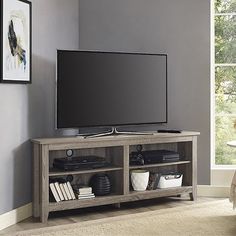 a flat screen tv sitting on top of a wooden entertainment center next to a window