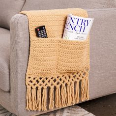 a couch with a remote control on it next to a magazine rack and a blanket