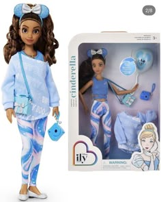 the doll is wearing blue pajamas and holding a handbag in her left hand while she stands next to an open box