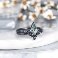 a close up of a ring on a white plate with flowers in the back ground