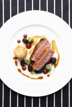 a white plate topped with meat and fruit