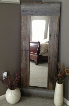 a mirror sitting on top of a floor next to two vases