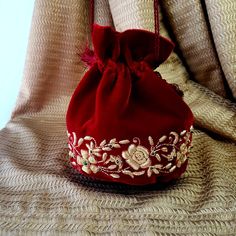 "The sweetest petite potli bag to enhance any outfit! Hand embroidered with pale gold metallic flowers on luxurious cream velvet and embellished with genuine semi precious stones to create an opulent effect. It is certain to bring you compliments. Perfect for Indian weddings! Expertly hand embroidered by third generation master zardozi artisans. Of heirloom quality. - Measures approx 7\" tall, base is 4\" across. - Useable interior space is 5 x 4\". - Wrist cord with tassel, 6 in. drop - Additio Metallic Flowers, Potli Bag, Wrist Bag, Embroidered Handbag, Wedding Red, Potli Bags, Wedding Purse, Handcrafted Bags, Indian Weddings