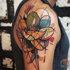 a colorful tattoo design on the arm and shoulder, with an abstract flower in the center