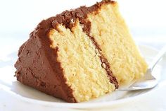 a slice of yellow cake on a white plate with a fork in front of it