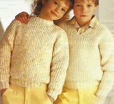 two young boys in sweaters and pants standing next to each other with their arms around one another