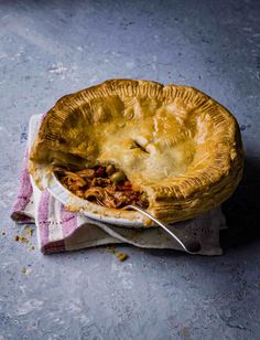 a close up of a pie on a napkin with a fork in it and a spoon sticking out of the pie