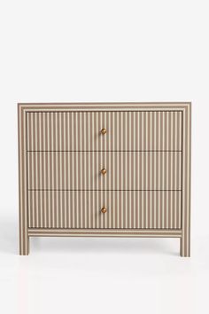 a white and brown striped chest of drawers with gold knobs on the front, against a white background