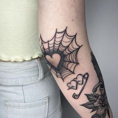 a woman's arm with a spider web and heart tattoo on the left forearm