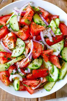 a white bowl filled with cucumber salad on top of a wooden table