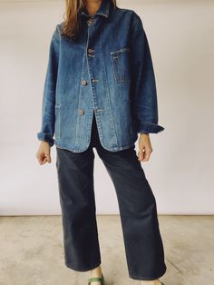 A person wearing The Barn Coat by Hey Gang, an oversized unisex Japanese denim jacket featuring large front pockets and brown buttons, paired with black wide-leg pants, stands against a plain background. Their hand is slightly raised. 2024 Moodboard, Barn Coat, Like Fine Wine, Chore Coat, Pilates Studio, Japanese Denim, 2023 Fashion, The Barn, Fine Wine