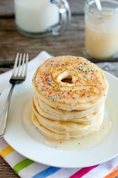 a stack of pancakes sitting on top of a white plate next to a glass of milk