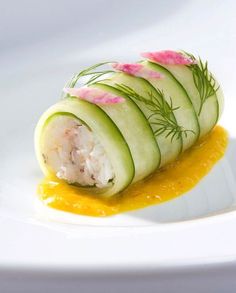 cucumber wrapped in fish fillet with orange sauce on white plate, closeup