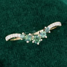 two green and white diamond rings sitting on top of a green velvet covered surface with grass in the background