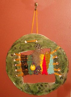 a green plate hanging from the ceiling in front of a red wall with pins and beads on it