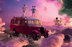 two people standing on top of an old car in the sky with clouds behind them