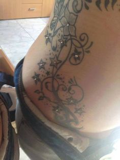 a woman's lower back tattoo with stars and swirls on the bottom side