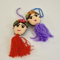 two small dolls with tassels on them sitting next to each other in different colors