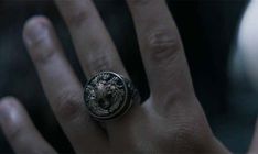 a person's hand with a ring on it that has a lion head in the middle