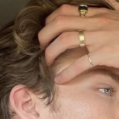 a close up of a person wearing two different rings on their hands and one with a ring on his head