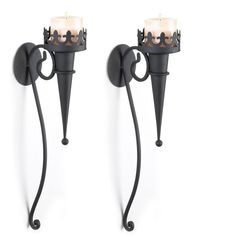 two black wrought iron wall sconces with candle holders on each side, one holding a lit candle