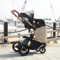 a baby stroller sitting on the ground next to a dock with boats in the background