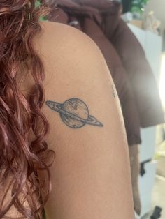 a woman with a small saturn tattoo on her arm