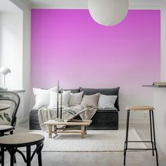 a living room with purple walls and white rugs on the floor, two stools in front of a black couch