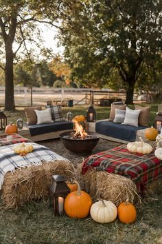 an outdoor fire pit surrounded by hay bales with pumpkins on the ground and plaid blankets