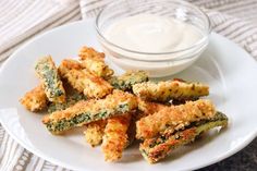 a white plate topped with fried vegetables next to a bowl of ranch dressing