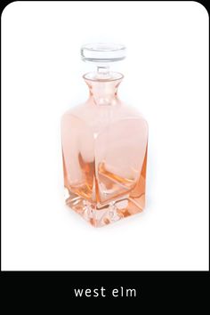 an empty pink glass bottle sitting on top of a white table next to the words west elm