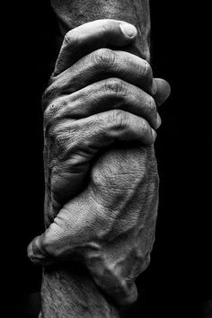 an old woman's hands holding the wrist of another person in black and white