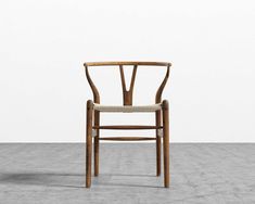 a wooden chair sitting on top of a cement floor next to a white wall in an empty room