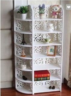 a white shelf with books on top of it next to a teddy bear and potted plant