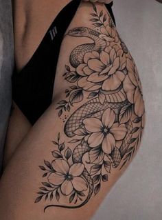 a woman's thigh with flowers and snake tattoo on the side of her leg