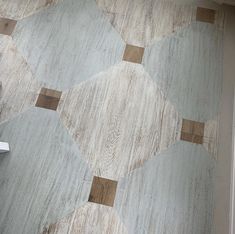 a white toilet sitting in a bathroom next to a wooden floor with tile on it