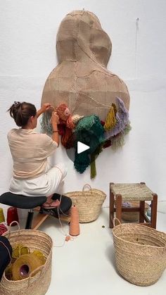 a woman sitting on the floor next to baskets with yarn and other items in them