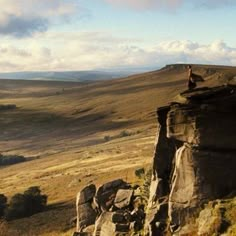 a person standing on top of a rock formation in the middle of a mountain range