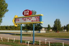 a large sign for the 12 eleven movie theater in front of a road and trees