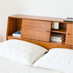 a bed with white pillows and a wooden cabinet