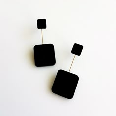 two black square shaped earrings on white background