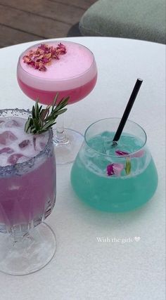 two cocktails sitting on top of a table next to each other with flowers in them