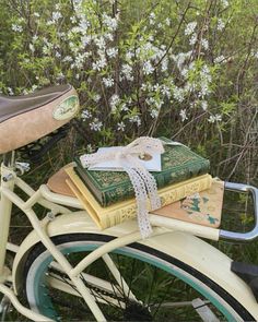 two books tied to the back of a bicycle with flowers in the background and grass