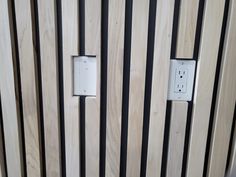 two electrical outlets are mounted to the side of a wooden paneled wall with black and white stripes