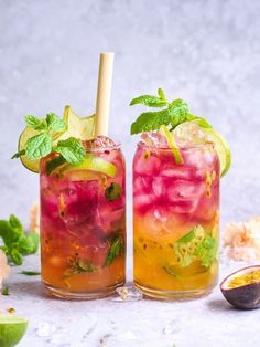 two glasses filled with drinks and garnishes next to an avocado