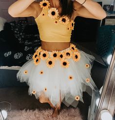 a woman in a yellow crop top and white tutu with sunflowers on it