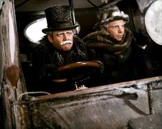 two men in hats and scarves driving a car