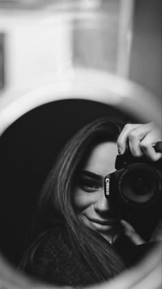 a woman taking a selfie in front of a mirror with her camera lens up