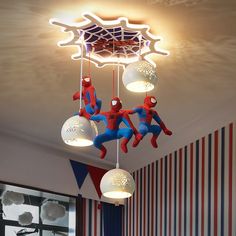 a spiderman themed ceiling light hanging in a child's room with striped walls